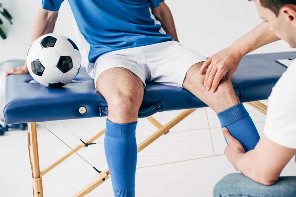 fisioterapeuta cuidando de um jogador de futebol
