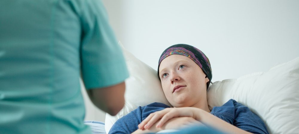 paciente deitada na cama de hospital conversando com psicóloga